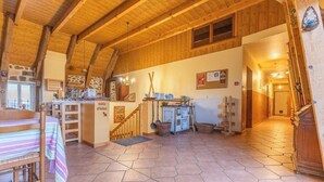Un interior rústico con una escalera de madera, un comedor con mesa y sillas, y una cocina con armarios y un radiador.