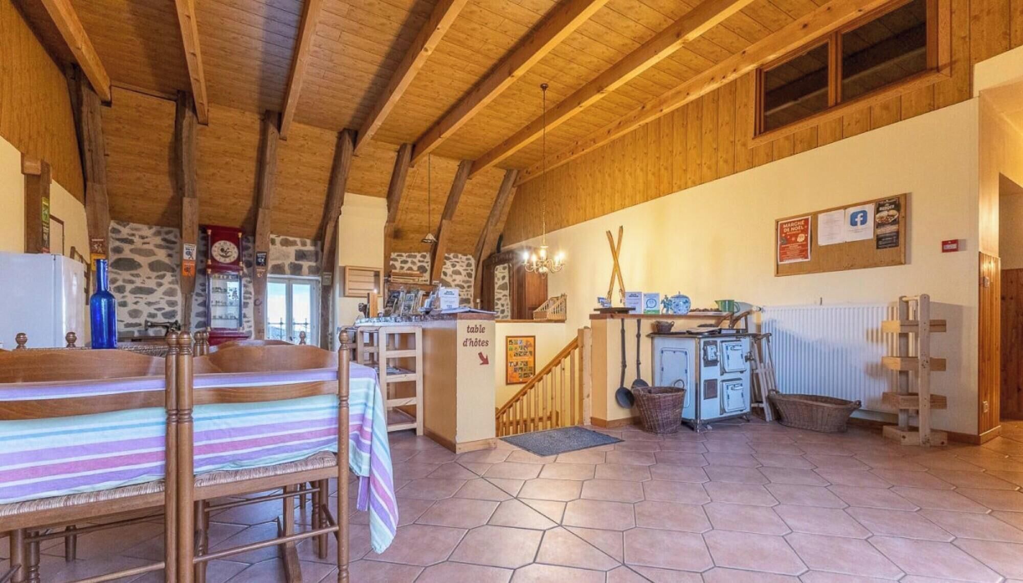Une cuisine rustique avec des poutres en bois, un mur en pierre et un sol carrelé.