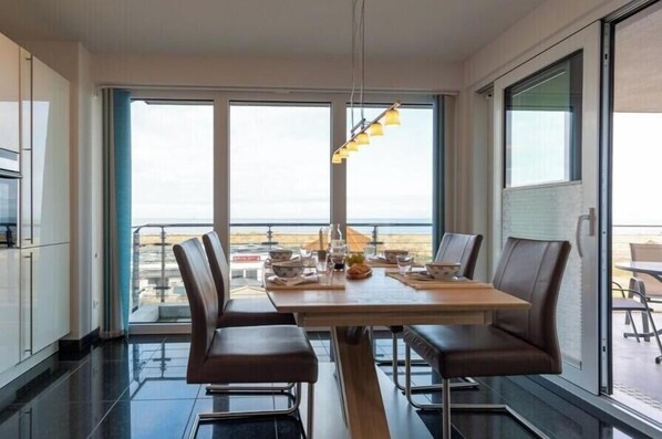 Un comedor con mesa y sillas, ventanas amplias y vistas al exterior.