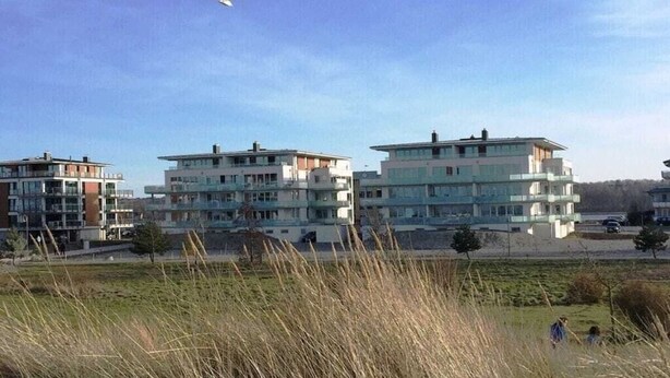 A residential area with modern multi-story buildings, a grassy field, and a clear sky. - Holiday apartment with 2 bedrooms (Heiligenhafen)