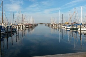 Ein Yachthafen mit mehreren Booten, die an Stegen liegen, ruhigem Wasser und einem klaren Himmel.