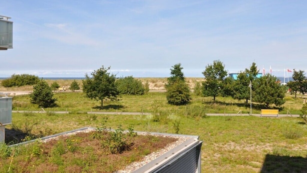 A grassy field with trees and a building in the distance. - Holiday apartment with 2 bedrooms (Heiligenhafen)