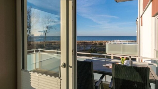 Ein Balkon mit Blick auf das Meer und ein Gebäude im Hintergrund.