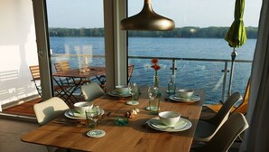 En spiseplads med et bord dækket til fire, med udsigt over vand.