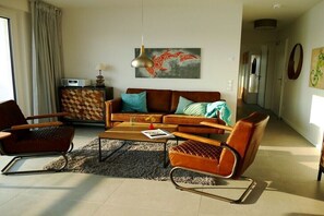 En moderne stue med sofa, to stole, sofabord og et tæppe.