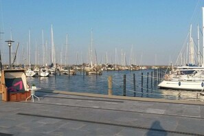 A marina with multiple boats docked, a small kiosk, and a clear sky. - Holiday apartment with 1 bedroom (Heiligenhafen)