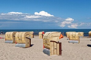 Des chaises de plage, chacune portant un numéro, sont disposées sur une plage de sable.