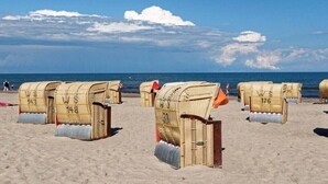 Sedie da spiaggia con numeri, disposte su una spiaggia sabbiosa.