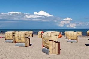 Beach chairs with numbers on them, arranged on a sandy beach. - Holiday apartment with 1 bedroom (Heiligenhafen)