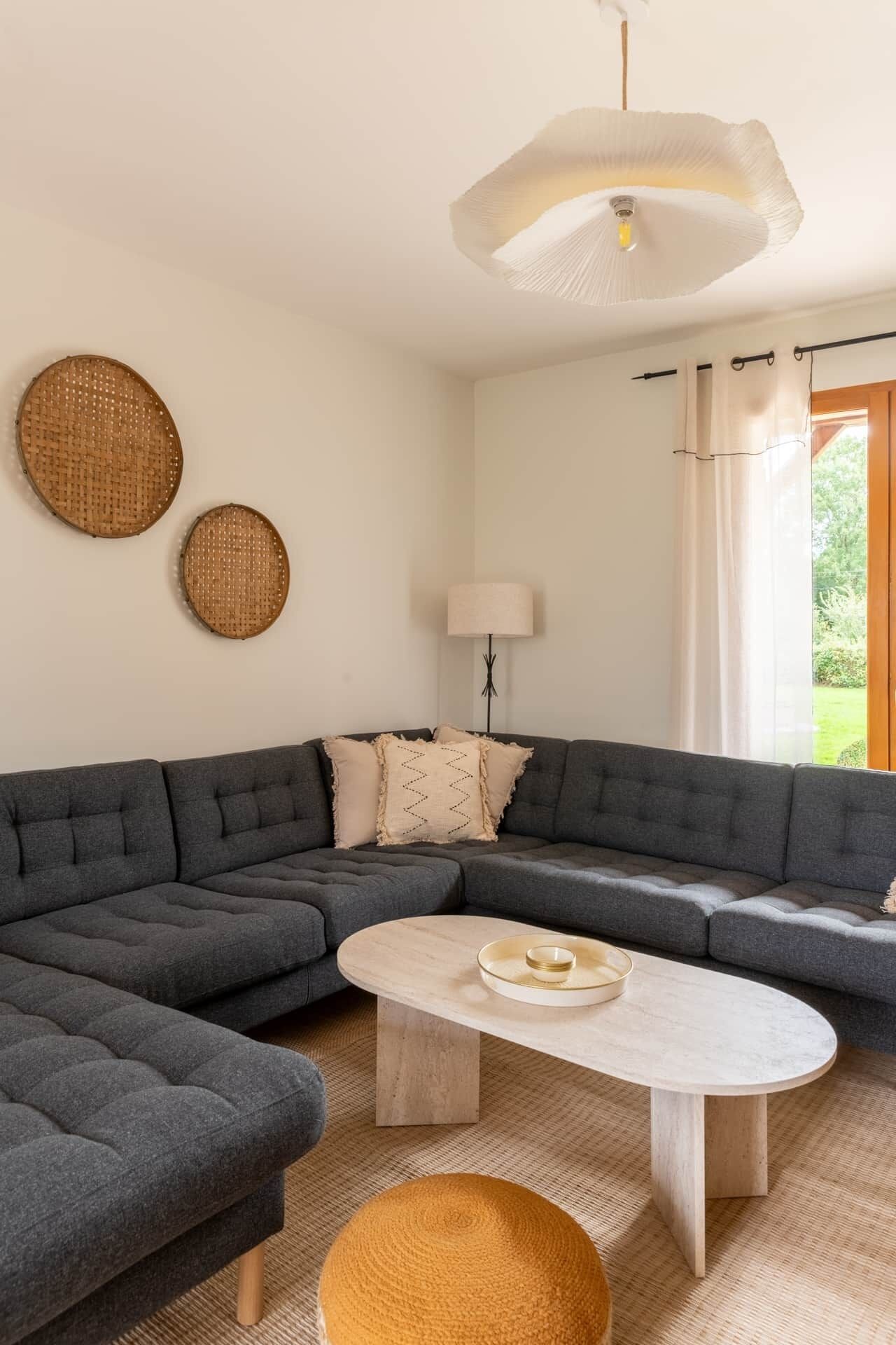 A modern living room with a grey sectional sofa, a round coffee table, and two woven wall decorations.