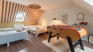 Een gezellige slaapkamer met twee bedden, een tafelvoetbaltafel en een schuine plafond met een raam.