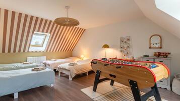 Une chambre confortable avec deux lits, un baby-foot et un plafond en pente avec une fenêtre.