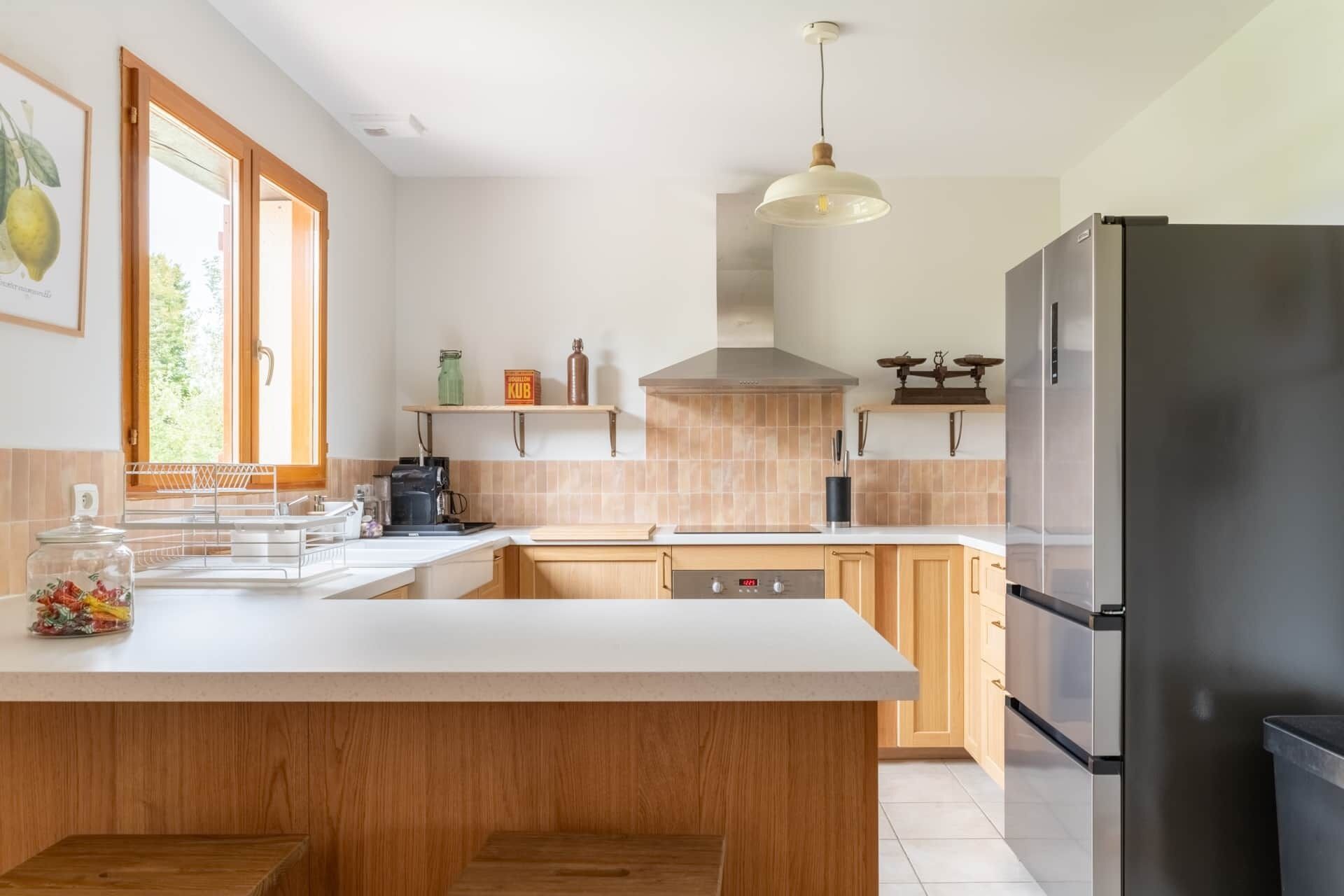 A modern kitchen with a large island, stainless steel appliances, and a hanging pendant light.
