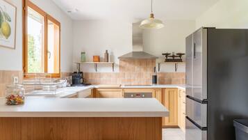 A modern kitchen with a large island, stainless steel appliances, and a hanging pendant light.