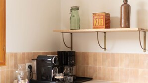 Een keuken met een koffiezetapparaat, een fles en een doos op een plank.