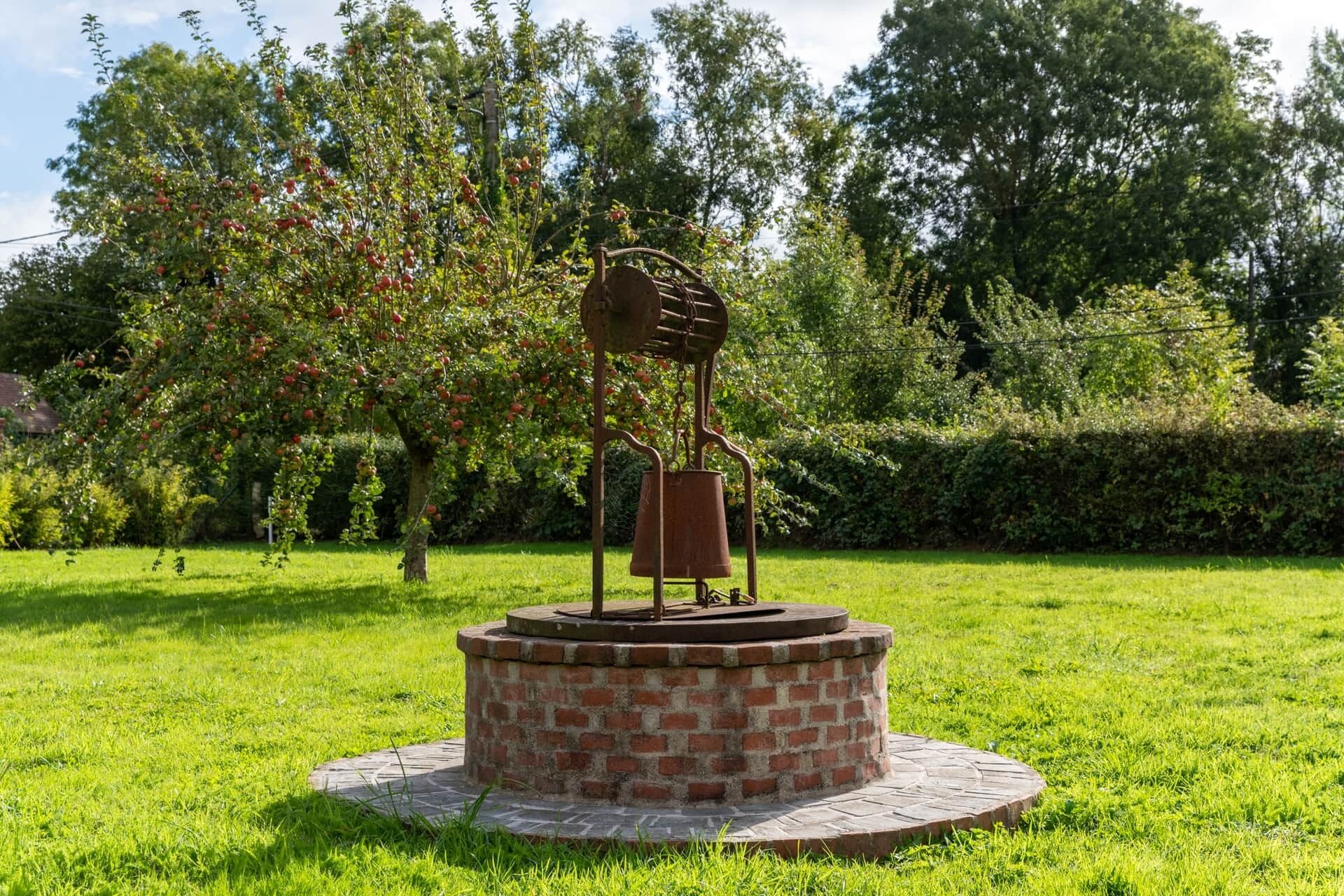 Une sculpture représentant une personne tenant une cloche dans un parc.