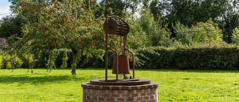 Une sculpture représentant une personne tenant une cloche dans un parc.