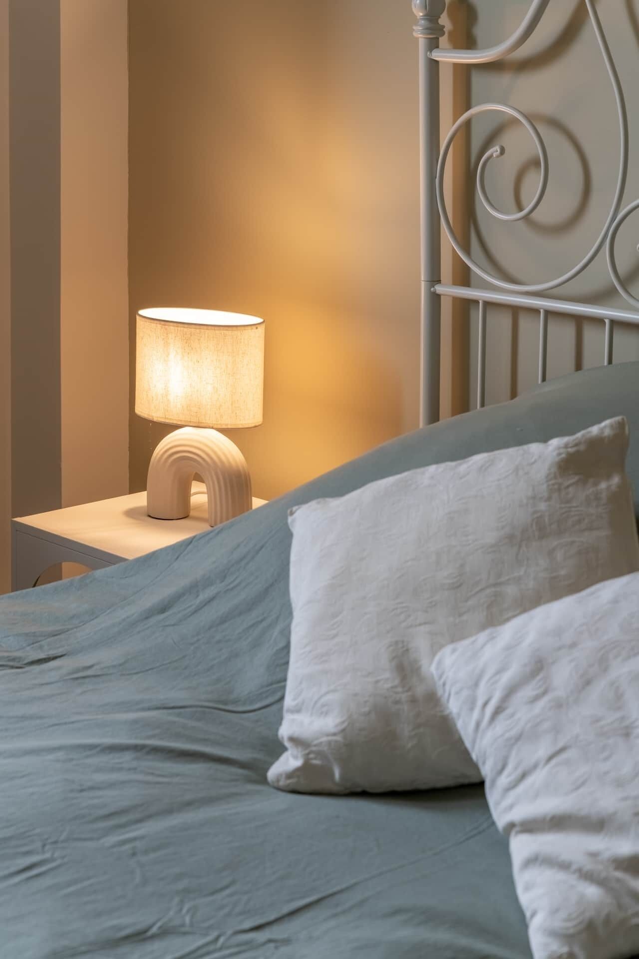 A bed with a headboard, a bedside lamp, and two pillows.