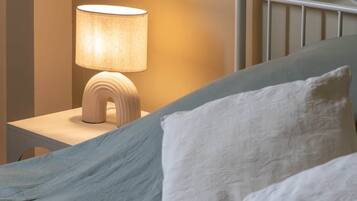 A bed with a headboard, a bedside lamp, and two pillows.