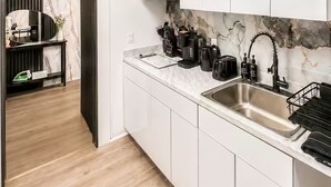 Cocina moderna con armarios blancos, un lavamanos de acero inoxidable y un microondas.