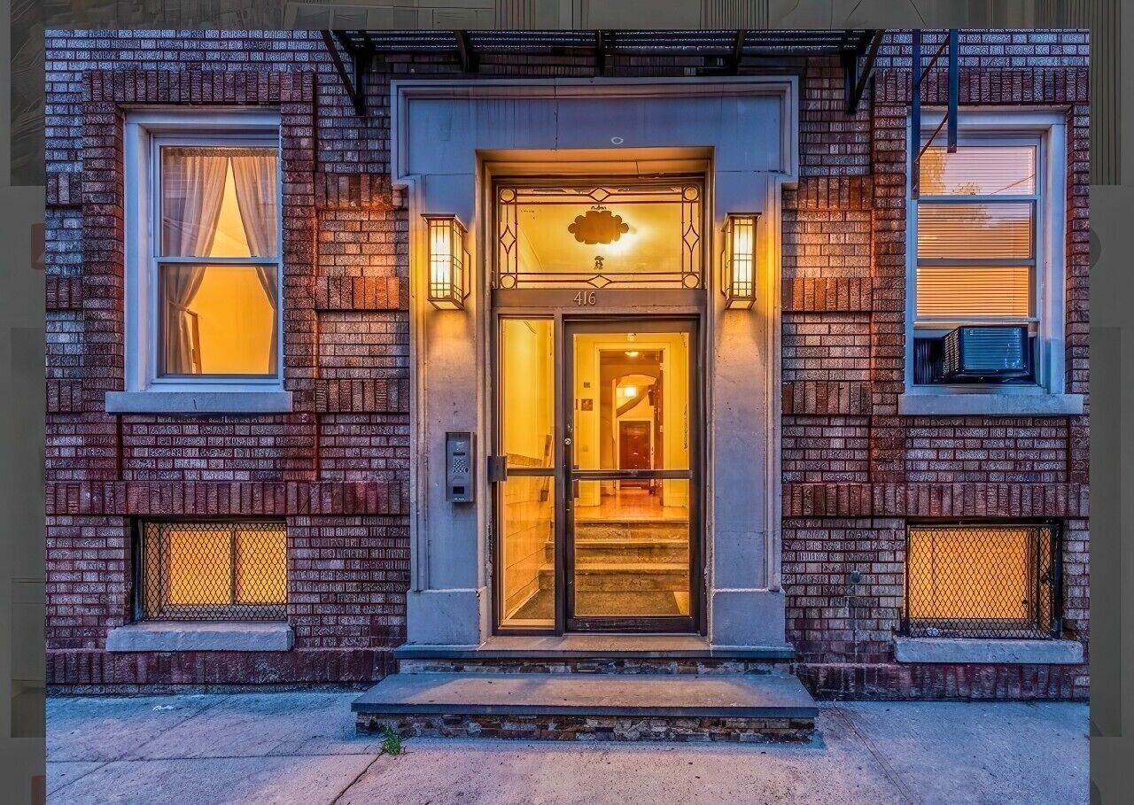 Un edificio in mattoni con ingresso in vetro, numero 416, e due piccole finestre con tende.