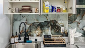 Een keuken met open kastjes waarin servies, glazen en keukengerei staan.