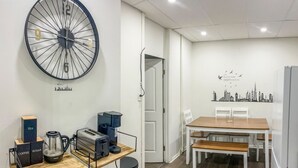 Een moderne keuken met een grote wandklok, een koffiezetapparaat, een broodrooster en een waterkoker op een houten aanrecht.
