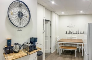 Eine moderne Küche mit einer großen Wanduhr, einer Kaffeemaschine, einem Toaster und einem Wasserkocher auf einer Holzarbeitsplatte.