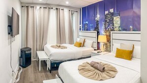 Een hotelkamer met twee bedden, een televisie, uitzicht op de stad en een raam met gordijnen.
