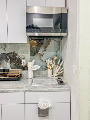 A modern kitchen with a built-in microwave, a marble backsplash, and a stainless steel range hood. - 20 Minutes to MetLife Stadium / Manhattan / FIFA 2026 (Apt. 2) (West New York)