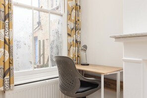 A room with a desk, chair, radiator, and a window with curtains. - New! Cosy Hackney 3BR | 7 Mins to London Fields (Greater London)