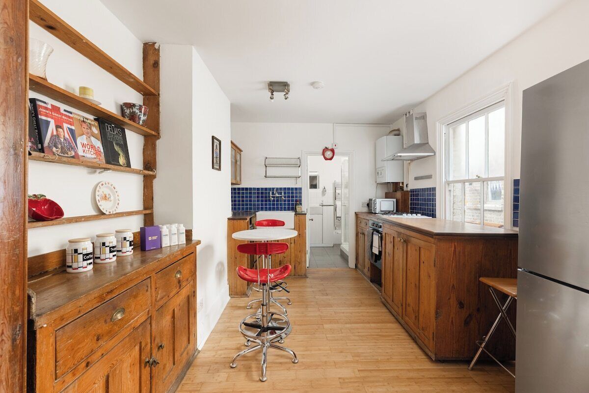 A kitchen with wooden cabinets, a stainless steel refrigerator, and a bar stool.