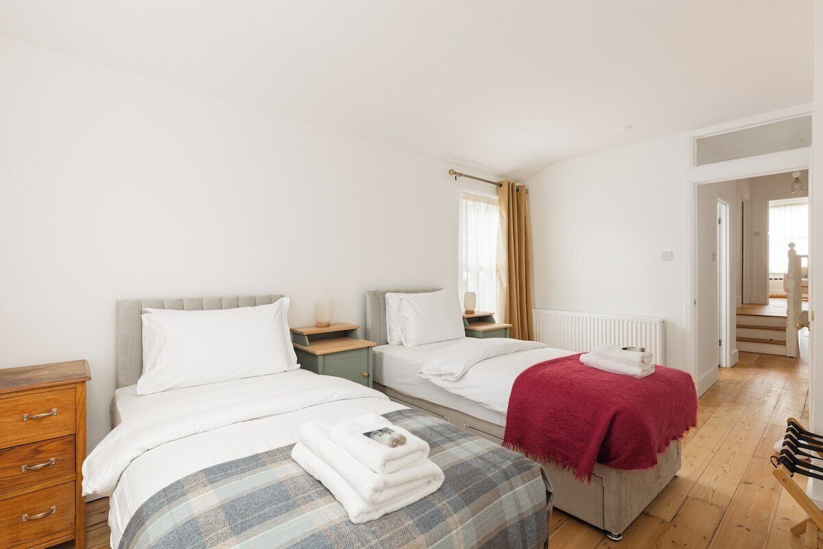A hotel room with two beds, a wooden dresser, and a view of the hallway.
