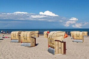 Beach huts with numbers on them, arranged on a sandy beach with the sea in the background. - Holiday apartment with 2 bedrooms (Heiligenhafen)