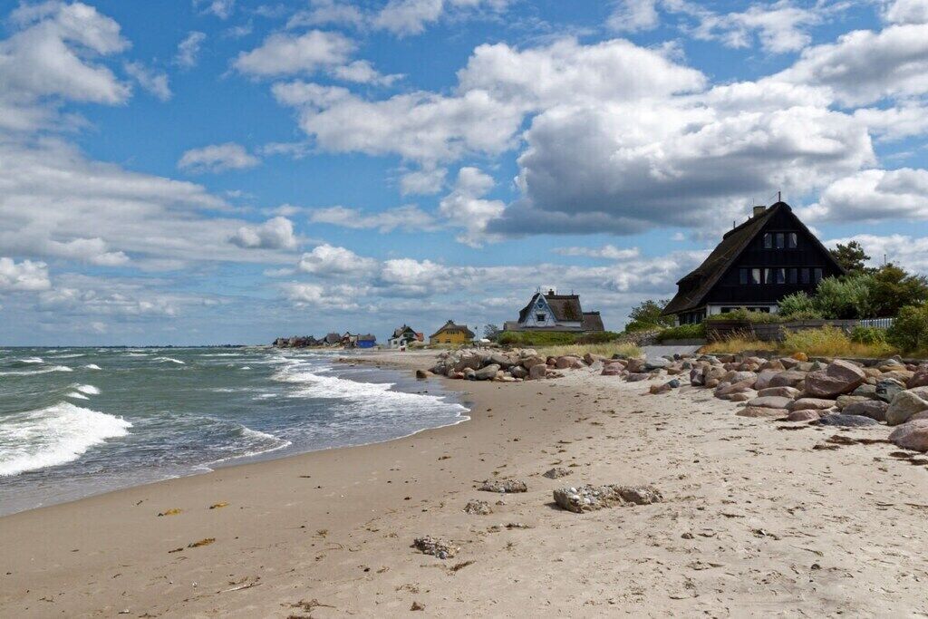 A beach with a house and a rocky shoreline.