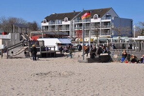 A beachside area with a playground, a building with multiple balconies, and a flagpole. - Holiday apartment with 1 bedroom (Großenbrode)