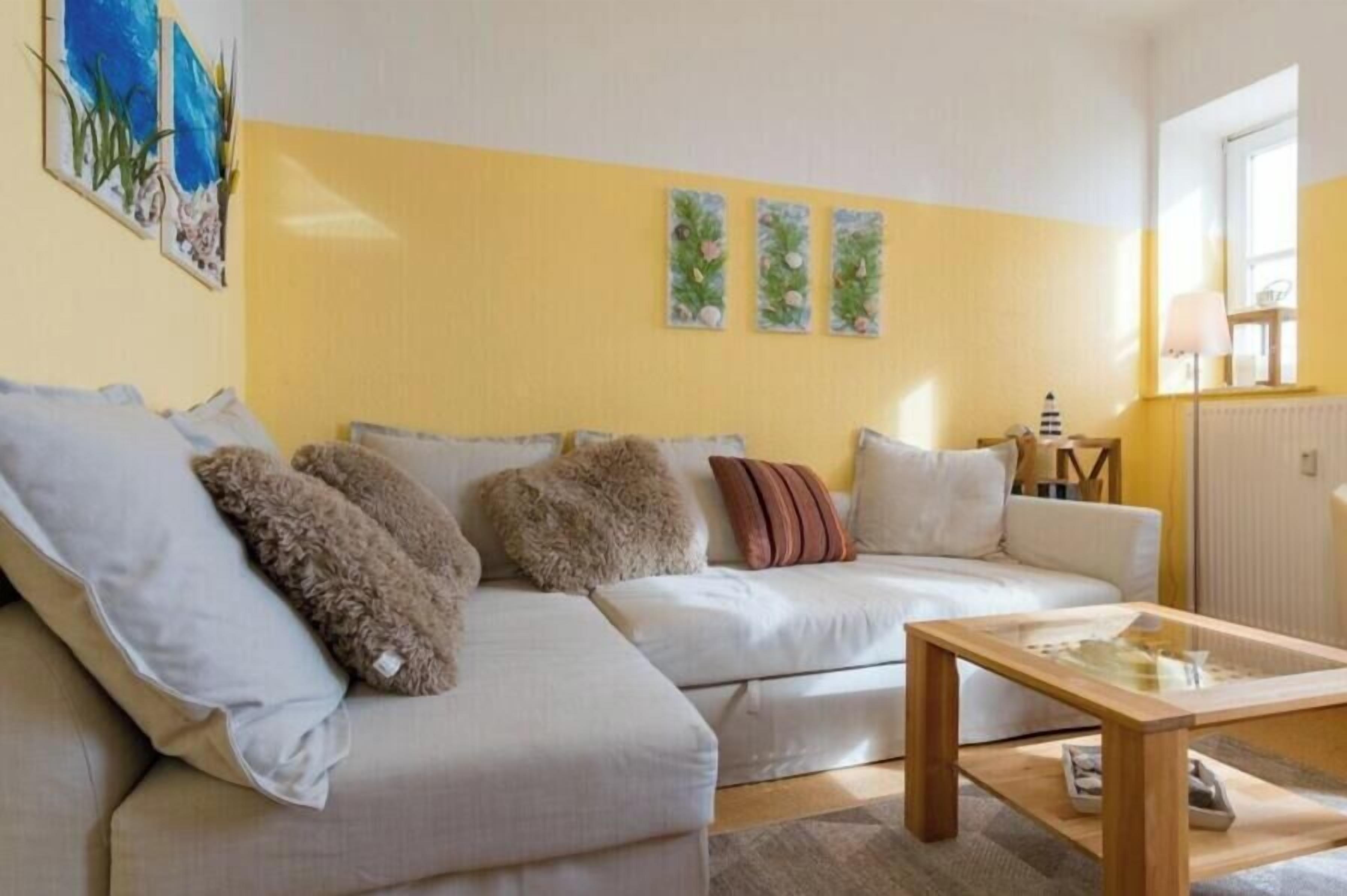 A living room with a sofa, cushions, a coffee table, and wall art.