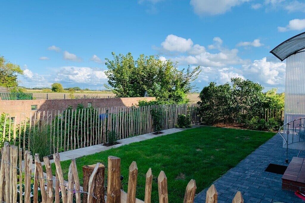 A well-maintained garden with a wooden fence, a paved pathway, and a grassy lawn.