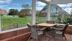 Un patio con mobili in vimini e vista su un campo verde.