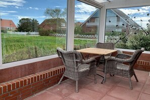 Eine Terrasse mit Korbmöbeln und Blick auf ein grünes Feld.