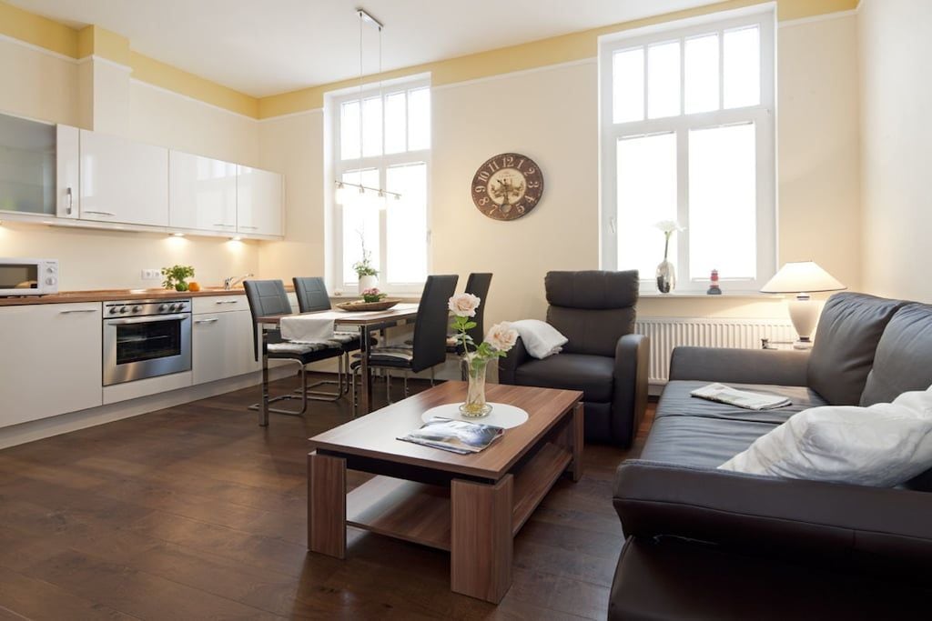 A modern living room with a sofa, a coffee table, and a dining area with chairs.