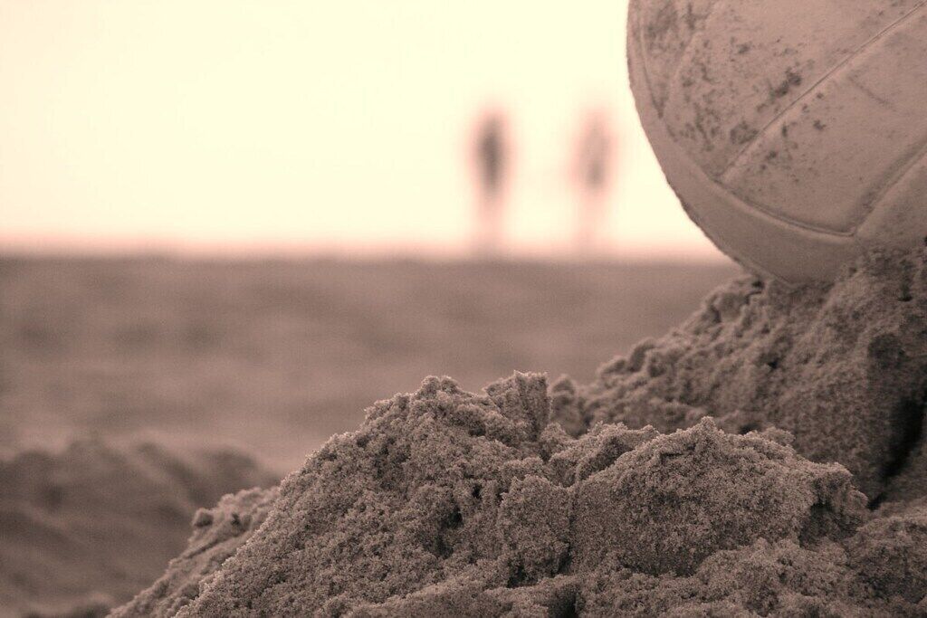 Volleybol en superficie arenosa, con fondo desenfocado.