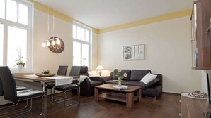 Ein Wohnzimmer mit einer Couch, einem Couchtisch und einem Essbereich mit Stühlen und Tisch.