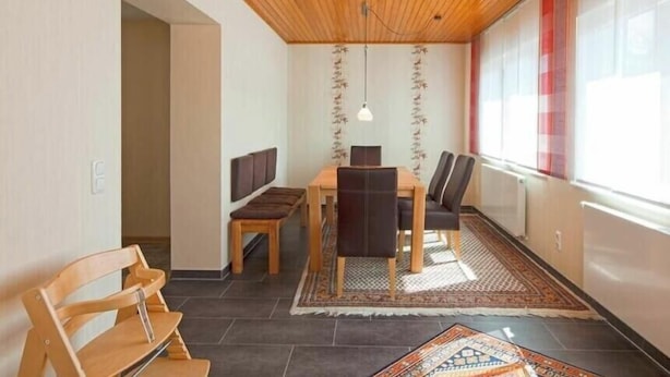 Ein Essbereich mit Holzboden, einem Tisch mit Stühlen und einem gemusterten Teppich.