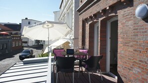 Ein Sitzbereich im Freien mit Tisch, Stühlen und einem großen Sonnenschirm.