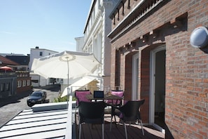 An outdoor seating area with a table, chairs, and a large umbrella. - Amelie (Villa Rossini) (Norderney)