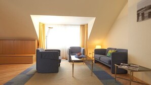 Ein modernes Wohnzimmer mit Sofa, Sessel, Couchtisch und Lampe.