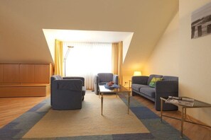 Una sala de estar moderna con sofá, sillón, mesa de centro y lámpara.