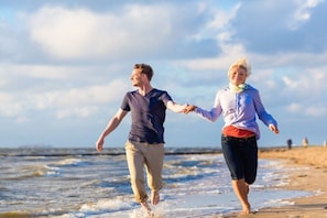 Dos personas caminando por una playa con el océano al fondo.