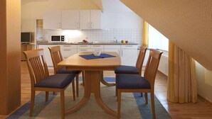 Ein Essbereich mit Tisch und Stühlen, einer Mikrowelle und Schränken im Hintergrund.